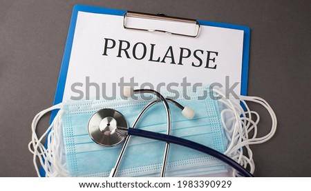 Folder with paper text PROLAPSE , on a table with a stethoscope and medical masks, medical