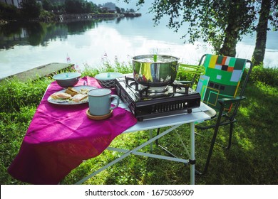 Folding camping table with items for cooking and food against a picturesque natural background in Norway. Summer vacation concept. A table with breakfast at a campsite on the background of a lake  - Powered by Shutterstock