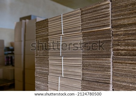 Folding cardboard boxes. Perforated sheets of corrugated cardboard are stacked on pallets. Packaging of finished products in industrial production.