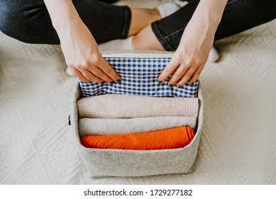 Folding clothes and organizing stuff in boxes and baskets. Concept of tidiness, minimalism lifestyle and japanese t-shirt folding system. Wardrobe storage system