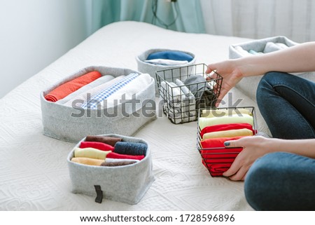 Folding clothes and organizing stuff in boxes and baskets. Concept of tidiness, minimalism lifestyle and japanese t-shirt folding system. Minimalist storage system and wardrobe