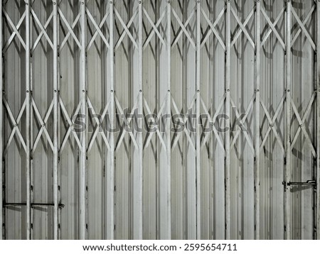 Folding gate of a shop from the inside is white with cross joints, made of iron and looks old