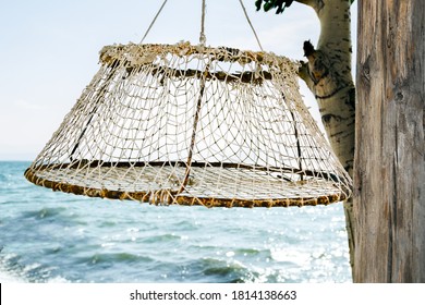 Folding Net For Catching Crayfish And Crabs Hanging On A Tree Against The Sea