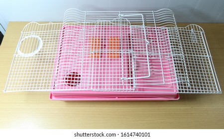 Folding Old And Empty White And Pink Hamster Cage On Wood Desk