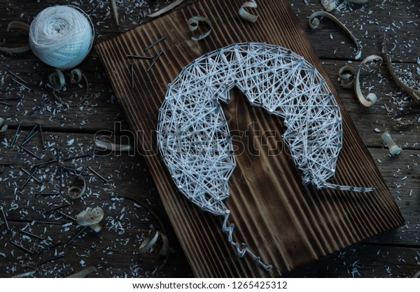 folk art of the Northern peoples of nails,\
white thread and boards as a\
background