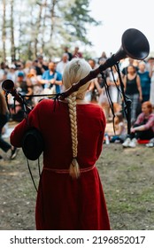 Folk Concert Outdoors. Back View Of A Woman Musician In A Medieval Costume Playing The Bagpipes.