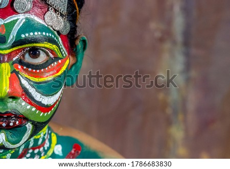 A folk theater artist putting colorful make-up