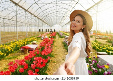 Follow Me Between Tulips In Spring Time. Young Woman Holding Man Hand Smiling Looking Back Between Rows Of Tulip Flowers.