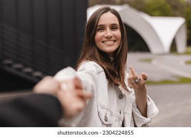 Follow me. Boyfriend following girlfriend holding hands, walking in city, copy space. Come with me. happy young woman pulling guy's hand, hand in hand, concept of carefree modern life. - Powered by Shutterstock