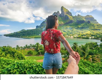 Follow me couple influencers tourists walking on Bora Bora island, Tahiti. Woman leading man off the beaten path exploring nature hiking trail in French Polynesia. Mt Otemanu wanderlust summer travel.