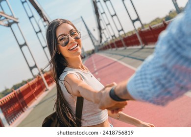 Follow me! Happy young woman pulling guy's hand in hand walking on a bright sunny day on the bridge. Romantic date. city exploration together, sightseeing - Powered by Shutterstock