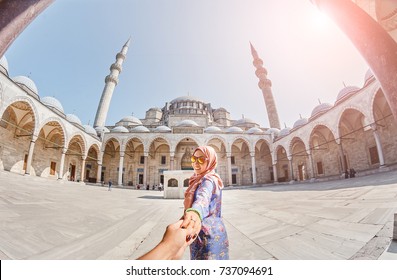 Follow me. A Muslim woman in a scarf leads her friend to the Turkish mosque Suleymaniye, travel and religion concept.