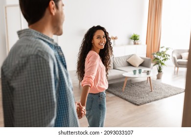 Follow Me. Portrait of happy lady inviting guy to enter home, welcoming to living room, happy smiling woman holding man's hand showing new modern apartment and living room, selective focus - Shutterstock ID 2093033107