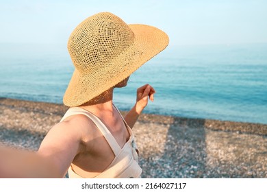 Follow me. Woman holds and pulls the photographer's hand while walking on the beach and leads her towards the sea. Concept of union and carefree modern life. Tourism in summertime.