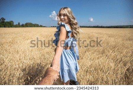 Follow me, young beautiful blonde woman in wheat field
