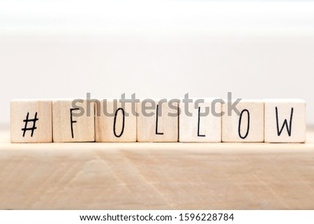 Follow sign made of cubes on a wooden table with Hashtag near white background, socialmedia concept close-up