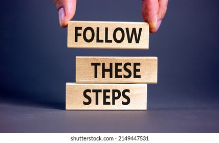 Follow these steps symbol. Concept words Follow these steps on wooden blocks. Businessman hand. Beautiful grey table grey background. Business and follow these steps concept. Copy space. - Shutterstock ID 2149447531