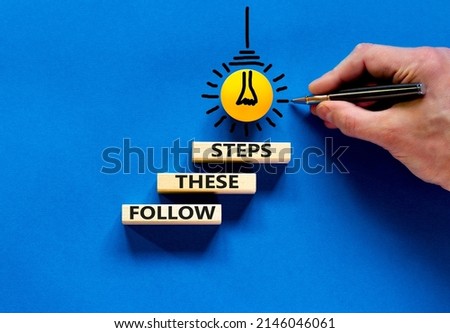 Follow these steps symbol. Concept words Follow these steps on wooden blocks. Businessman hand. Yellow light bulb icon. Beautiful blue background. Business and follow these steps concept. Copy space.