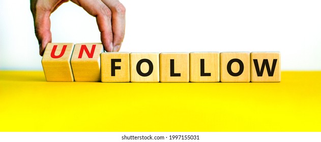 Follow or unfollow symbol. Businessman turns wooden cubes and changes words follow to unfollow. Beautiful yellow table, white background, copy space. Business and follow or unfollow concept.