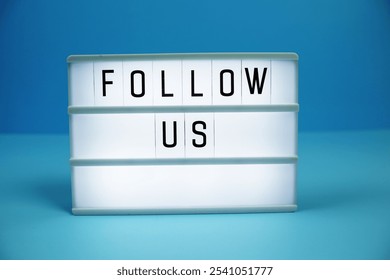 Follow Us letterboard text on LED Lightbox on blue background - Powered by Shutterstock