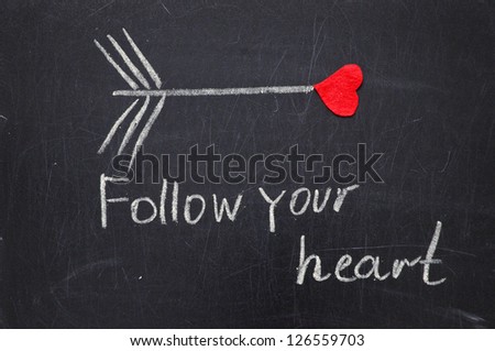  FOLLOW YOUR  HEART phrase by hand on a blackboard