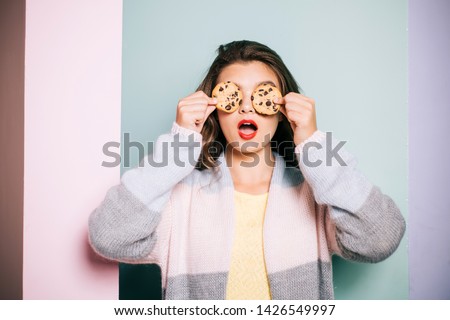 Following a cooking recipe. Pretty girl covering eyes with cookies. Cute girl having fun with cookies. Bakery style chocolate chip cookie recipe. Bakery shop. Getting perfectly thick cookies.