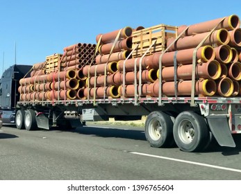 FOLSOM, CA, USA - MAY 1, 2019: Semi truck on the road carrying large pipes.