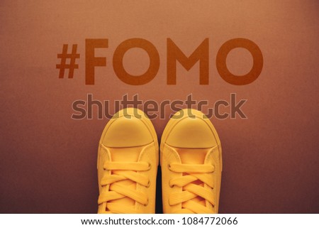 FOMO, fear of missing out concept with yellow sneakers from above.