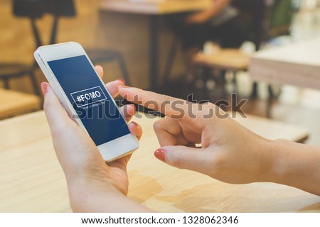 FOMO, fear of missing out concept. Female hand holding smartphone