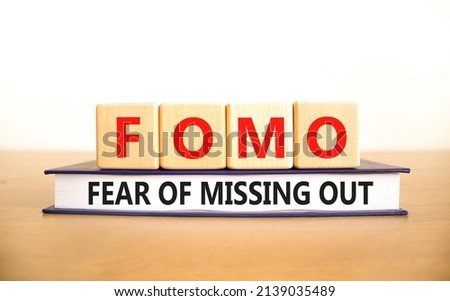 FOMO fear of missing out symbol. Concept words FOMO fear of missing out on wooden cubes on book on a beautiful white background. Copy space. Business FOMO fear of missing out concept.