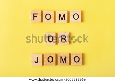 FOMO or JOMO written on yellow background. Choice, social problem concept. Top view