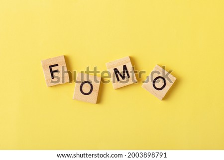 FOMO written on yellow background. Choice, social problem concept. Top view