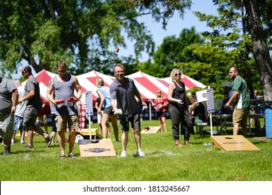 Fond du Lac, Wisconsin / USA - June 8th, 2020: Males and females play bean bag toss game at walleye weekend event at lakeside park as a community get together. 