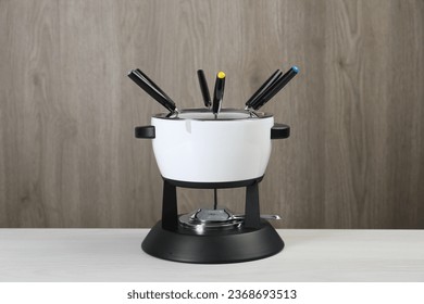 Fondue set on white wooden table. Kitchen equipment - Shutterstock ID 2368693513