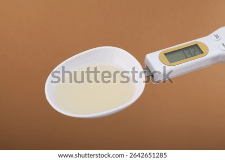 Food Additive E433 in plastic digital spoon scale, close-up. Polyoxyethylene (20) sorbitan monooleate or Polysorbate 80. Emulsifier and stabilizer. Versatile additive used wherever water-oil mixing.