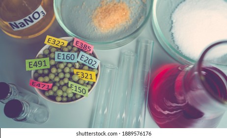 Food additives: chemical additives in the form of granules with colored labels, sodium nitrate in a flask, sugar and glutamate on a laboratory bench. Top view.