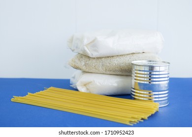 Food Aid During Quarantine. Products: Sugar, Rice, Pasta, Canned Food. Food Donation On A Blue Background.