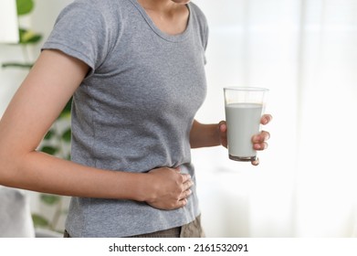 Food Allergy Milk Lactose Allergen Health Care Illness Concept. Close Up Hand Of Young Asian Woman Holding Stomach Belly Feel Pain Unhappy After Drink A Glass Of Milk.