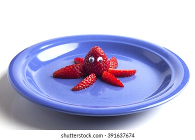 Food Art Creative Concepts. Cute Octopus Made Of Strawberries On A Blue Plate Isolated On White Background.