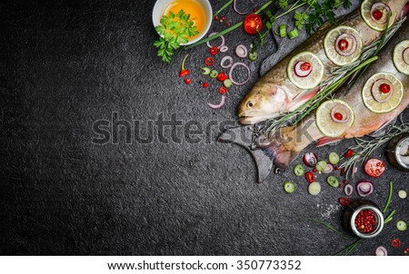 Food background for fish dishes cooking with various ingredients. Raw char with oil, herbs and spices on cutting board , top view.Healthy food or diet nutrition concept.