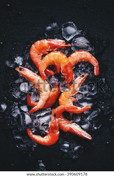 Food background, frozen cooked shrimp with ice,\
black background, top view