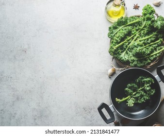 Food Background With Green Kale Leaves, Black Cooking Pan, Olive Oil, Anise And Garlic On Grey Concrete Kitchen Table. Healthy Cooking At Home With Seasonal Winter Vegetable.Top View.Copy Space. Frame