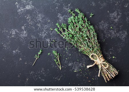 Food background of herb thyme on black kitchen table from above