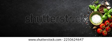 Food background on black stone table with vegetables, herbs and spices. Long banner format.