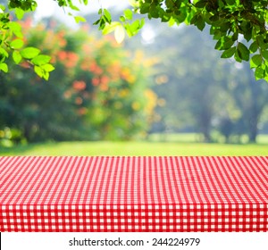 Food Background, Picnic Table With Tablecloth For Food, Product Display Over Blur Green Nature Outdoor Background, Table Top, Desk Cover With White And Red Pattern Clothing And Blurred Garden