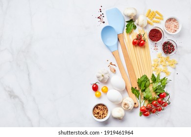 Food background with place for text, with different kinds of pasta, tomatoes, herbs, mushrooms, eggs, seasonings scattered on light marble background, top view. Italian cuisine concept - Powered by Shutterstock