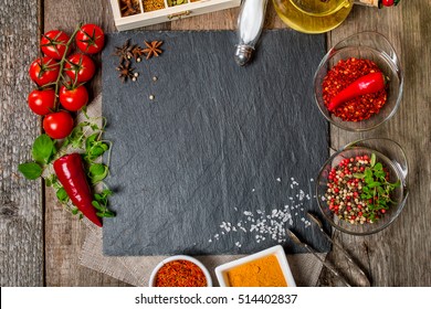 Food background, with space for text, herbs, spices, olive oil, salt, and vegetables. Slate and wood background. Top view