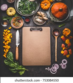 Food Background For Tasty Winter And Autumn Dishes With Pumpkin. Various Cooking Ingredients With Spoon And Knife Around Blank Cardboard Clipboard For Menu Or Recipes , Top View, Frame, Mock Up