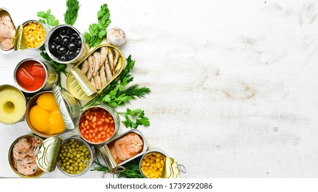 Food Background In Tin Cans. Canned Vegetables, Beans, Fish And Fruits On A White Wooden Background. Top View.