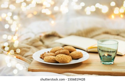 food, bakery and hygge concept - oatmeal cookies on plate and candle in holder at home - Powered by Shutterstock